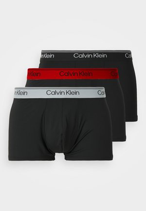 Boxeri Calvin Klein de culoare neagră, cu brâuri roșii și gri, decorate cu logo-uri. Material neted, design ajustat și lungime până la mijlocul coapsei.