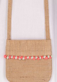 Kudottu säikä kuvioinen olkalaukku, jossa on litteä muoto, beige väri ja värikkäät pom-pomit alareunassa vaaleanpunaisina ja vihreinä.