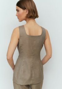 Top marrone senza maniche con scollo quadrato, design aderente e tessuto liscio e lavorato. Il retro presenta dettagli minimi, esaltando la semplicità.