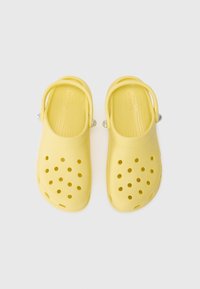 Yellow clogs with a glossy finish, featuring ventilation holes, a rear heel strap, and a textured footbed for comfort.