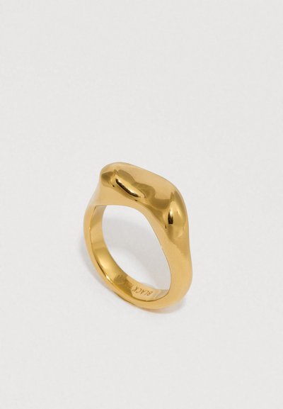 Inel din metal neted, auriu, cu o formă organică, rotunjită. Prezintă o ușoară neregularitate pe suprafață, creând o textură unică.