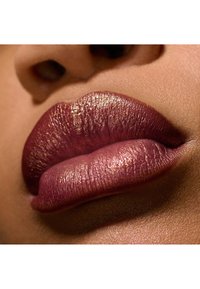 Des lèvres pulpeuses d'une couleur bourgogne profonde, avec un éclat métallique, mettant en valeur une texture lisse et des contours définis sur un fond neutre.