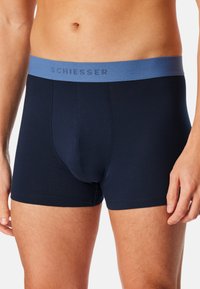 Marineblauwe heren boxershorts van zacht materiaal, met een lichtblauwe elastische tailleband met het "SCHIESSER" logo, een strakke pasvorm en een gladde textuur.