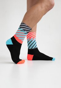 Schwarze und türkisfarbene Socken mit diagonalen Streifenmustern in Pink, Schwarz und Hellblau. Mit kontrastierenden Farben an Zehen und Fersen.