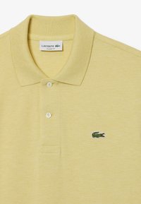 Geel katoenen polo shirt met een gestructureerde afwerking, twee-knopen sluiting en een klein groen krokodillenlogo op de linkerborst.