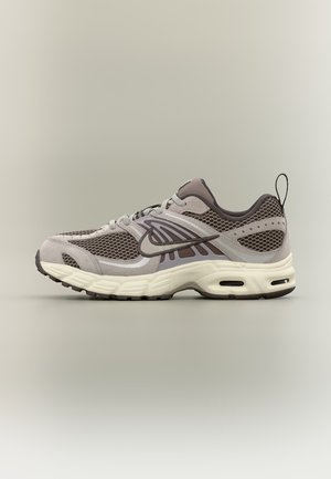 Chaussure de course Nike grise et beige avec panneaux en mesh, design à lacets, col matelassé et semelle amortissante avec des poches d'air.