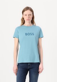 Šviesiai mėlyna medvilninė marškinėliai su trumpomis rankovėmis ir apvalia iškirpte, ant krūtinės su tamsiai mėlynomis raidėmis užrašyta "BOSS".