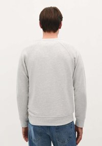 Grå crewneck sweatshirt med ribbede manchetter og kant, lavet af blødt bomuldsblend, med et enkelt design uden synlige mønstre.