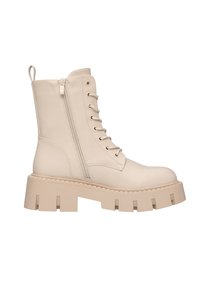 Stivale alla caviglia in pelle sintetica beige con suola piatta chunky, lacci frontali e zip laterale. Presenta un'etichetta di trazione sul tallone.