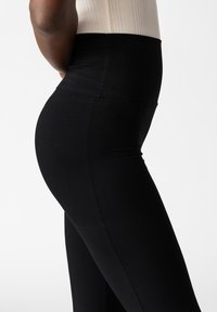 Hoge taille zwarte leggings gemaakt van rekbaar materiaal, met een naadloos ontwerp en een gladde textuur. Geen zichtbare logo's of patronen.