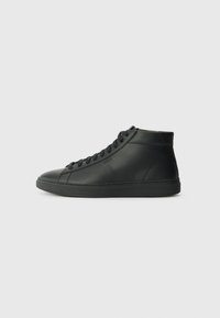 Zapatillas altas negras de cuero texturizado, con punta redondeada, suela de goma plana y cierre de cordones en la parte delantera con un sutil detalle de marca.
