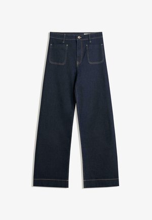 Jean large en denim bleu foncé avec des coutures contrastantes beiges, deux poches arrière et une fermeture à boutons à la taille.