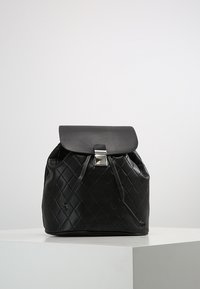 Sac à dos en cuir synthétique matelassé noir avec une forme arrondie, fermeture à rabat et ferrures de couleur argentée. Doté d'un cordon de serrage et d'une texture lisse.