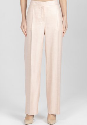 Beżowe szerokie spodnie z wysokim stanem noszone z beżowymi szpilkami z wąskim noskiem, pokazane na stojącej osobie na jednolitym tle.