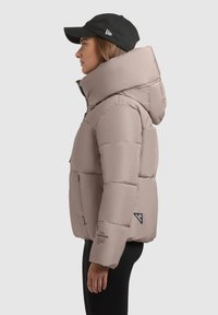 Gaisza beisbola jaka ar augstu apkakli, ar rāvējslēdzēja priekšpusi un divām sānu kabatām. Iekļauj logo uzlīmi un ribotas aproces. Valkā melnu cepuri.