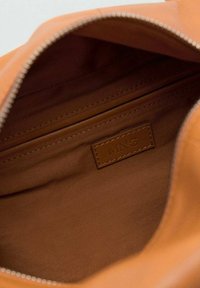 Tasseninterieur van tan stof met een ritszak en een gestikt leren label met 'MNG.' erop gedrukt.