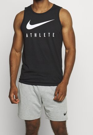 Débardeur noir sans manches avec le texte "ATHLETE" en blanc et le logo Nike. Associé à un short gris clair avec un petit logo Nike noir.