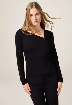 Zwart langslievend top met een gedraaid decolletée en diagonale naaddetails, gemaakt van een gladde stof, gecombineerd met bijpassende zwarte broek.