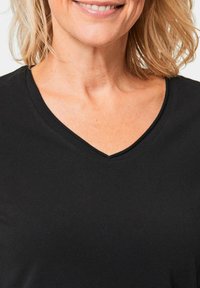 Zwarte V-hals t-shirt gemaakt van zachte katoen, met een gladde textuur en een klassieke snit rond de halslijn voor een ontspannen pasvorm.