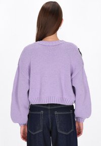 Lavaņu adītas džemperis ar īsu dizainu, ribotu apakšmalu un līdzīgu piedurknēm. Apvienots ar augsto vidukļa tumšo džinsu.