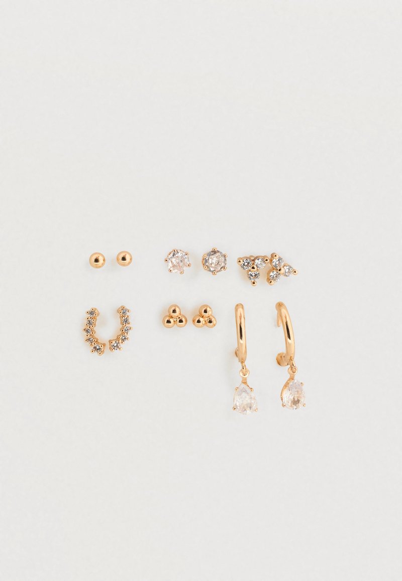 Sæt af øreringe i guldfarvet tone med stiftstile, øreringe med ringe og hængende detaljer samt dekorative elementer, herunder klare ædelsten og indviklede designs.