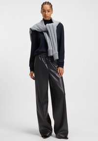 Navy sweater, gray ribbed scarf draped collar, black pleated wide-leg pants with a shiny finish, minimalistic design and neutral colors.