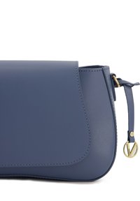 Blå læder clutch taske med en bølget silhuet, guld hardware og synlige syninger. Har en sidelæderkvast som accent.