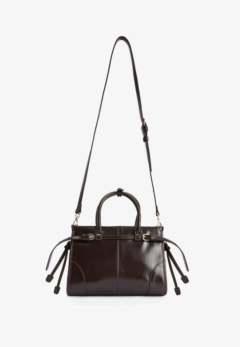 Dunkelbraune Lederhandtasche mit glänzender Oberflächenbeschaffenheit, ausgestattet mit zwei Obergriffen, einem abnehmbaren Schultergurt und seitlichen Fransen.