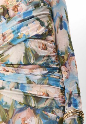 Indumento a maniche lunghe con arricciature strette e stampa floreale astratta nei toni del blu, verde, rosa e beige, indossato con numerosi bracciali d'oro.