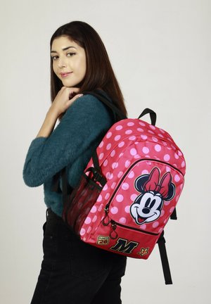 Mochila rosa con lunares blancos, con un gráfico de Minnie Mouse, bolsillo lateral de malla y acento con "M". Fabricada en material sintético duradero.