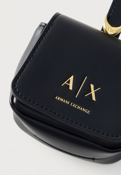 Черна кожена чанта Armani Exchange със златно лого A|X и надпис отпред, показваща шити краища и част от прикрепянето на дръжката.