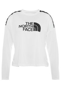 Vit långärmad topp med rund halsringning. Har en svart logotryck och svarta accenter vid axlarna. Slät tygtextur.