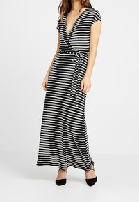 Černobílé pruhované maxi šaty s hlubokým výstřihem do V, krátkými rukávy a zavazovacími pasem. Hladký materiál s volným střihem.