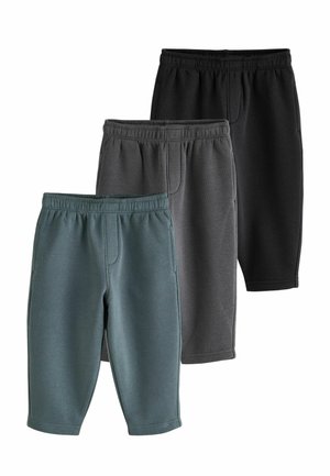 Tre par joggingbukser med elastisk talje i sort, mørkegrå og afdæmpet grøn, arrangeret i en forskudt bunke på en hvid baggrund.