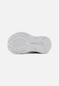 Witte sneakerzool met een gestructureerd oppervlak, voorzien van groeven en richels voor grip, en 'Skechers'-branding in reliëf.