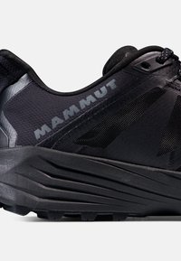 Svart atletisk sko med en strukturerad mesh-övre, kontrasterande detaljer, framträdande varumärkeslogotyp och en tjock, formad sula för dämpning.