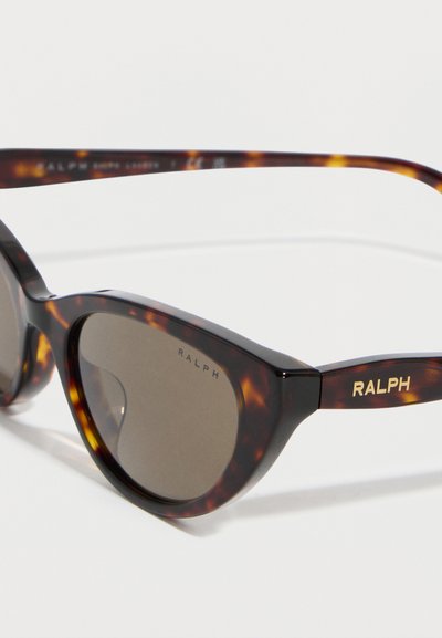 Katteøje-solbriller i skildpaddemønster med mørke linser og "RALPH"-logo i guld på stængerne og tæt ved linsekanten.