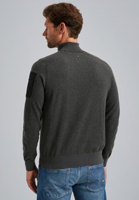 Dunkelgrauer Pullover mit hohem Kragen und schwarzem Schulterpatch. Verfügt über gerippte Bündchen und Saum, glatte Textur und figurbetontes Design.