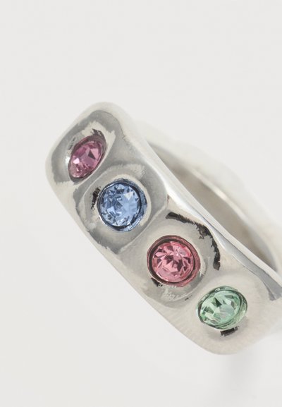 Bague en argent avec quatre pierres précieuses rondes rose, bleue, rose et verte alignées sur un anneau lisse.