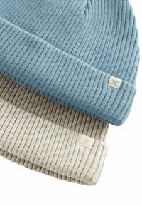 Due cappelli a coste: uno in azzurro chiaro, l'altro in beige. Entrambi presentano una texture morbida e piccole etichette di tessuto con un logo a stella.