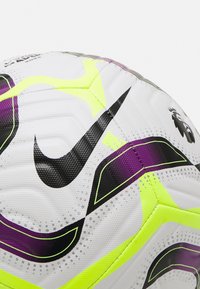 Pallone da calcio bianco con accenti neri e viola, caratterizzato da una superficie texturizzata, pannelli esagonali e elementi di design giallo neon.