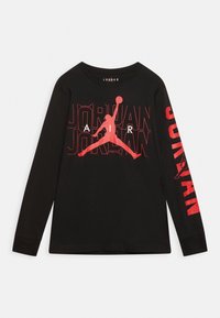 Černé tričko s dlouhými rukávy, které má velký červený grafický design loga Jumpman a text "JORDAN", s texturovanými detaily a kulatým výstřihem.