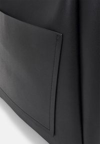 Czarna skórzana torba o gładkiej teksturze, wyraźnej przedniej kieszeni i subtelnych detalach w stębnowaniu. Prosty i funkcjonalny design.