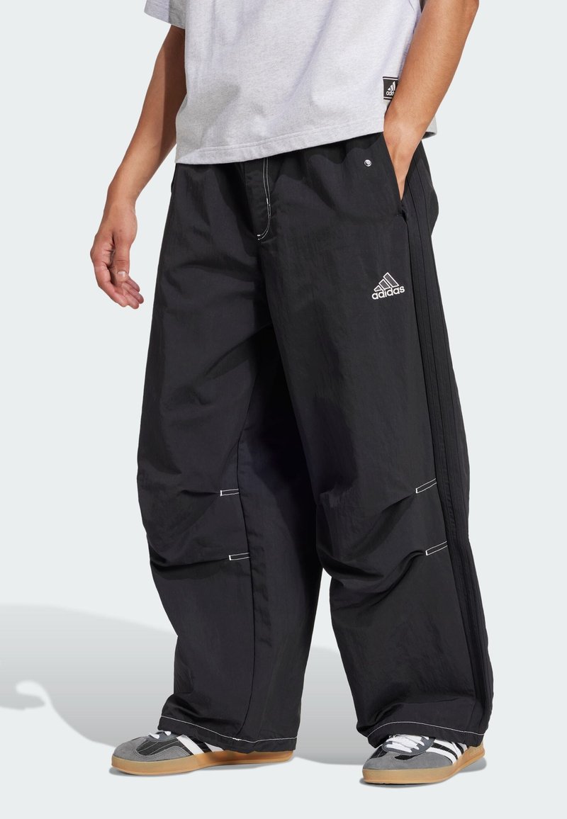 Melnas, brīva piegriezuma bikses ar teksturētu apdari, ar baltu akcentu šuvēm un izšūtu Adidas logo. Sānu rāvējslēdzis regulēšanai.