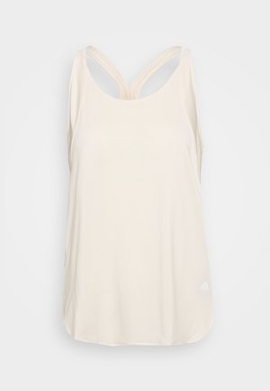 Light beige tank top made of smooth fabric, featuring a scoop neckline and double straps that cross at the back. Subtle logo at the hem.