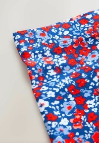 Tessuto a motivo floreale con sfondo blu e fiori rossi e bianchi. Tessitura liscia, materiale leggero, dettaglio orlo arrotolato.