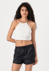 White halter crop top with a gathered neckline and small logo, paired with black elastic waist athletic shorts with side pockets.
