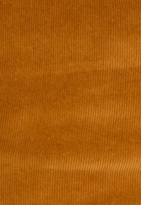 Tissu en velours côtelé de couleur marron doré chaud, avec des côtes verticales, une texture douce et un motif uniforme.