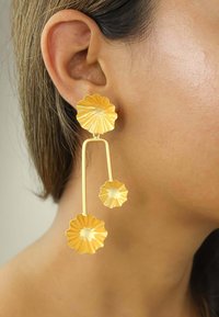 Guldmetallörhängen med en blommig design och texturerad finish. Örhängena har en trelagersstruktur och olika blombladformer.