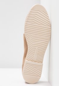 Bottine beige clair avec une tige en daim souple et une semelle en caoutchouc texturée, présentant un motif en zigzag et une étiquette de taille 37.